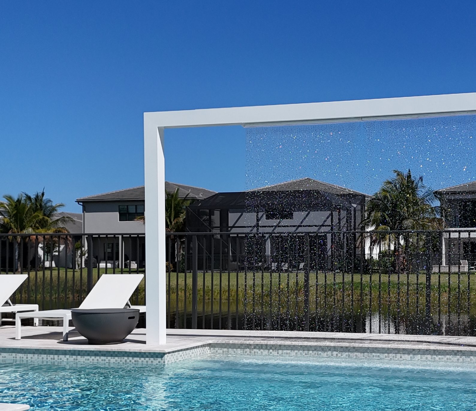 The white portal with the rain curtain falling into the pool, lake behind