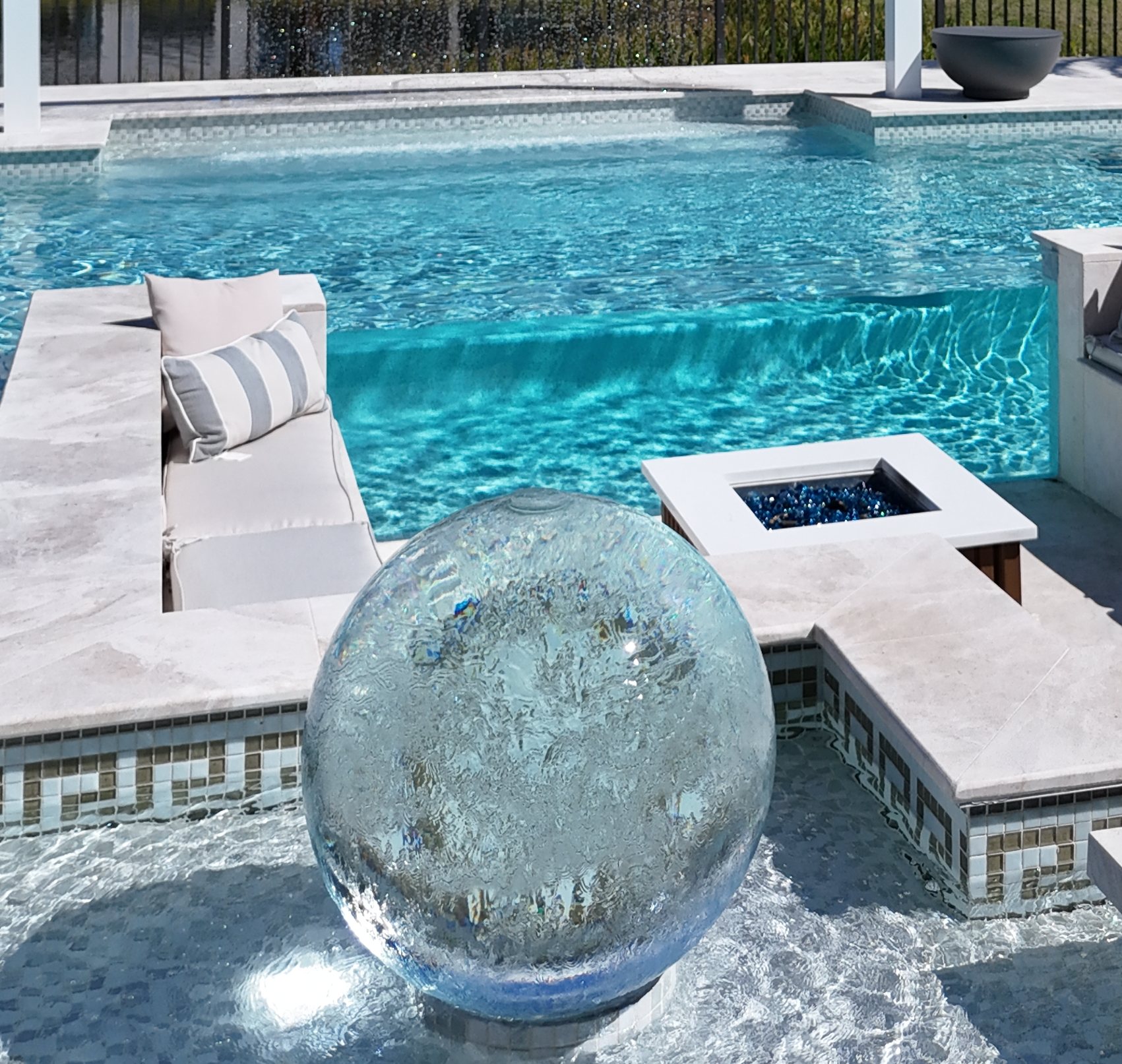 Crystal sphere and fire bowl at the pool edge with the Greek-key mosaic band