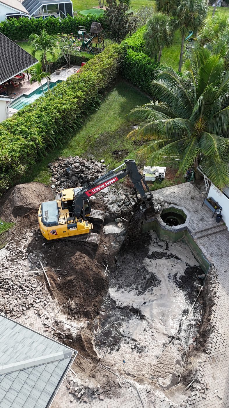 Excavator demolishing the old pool and deck, seen from above