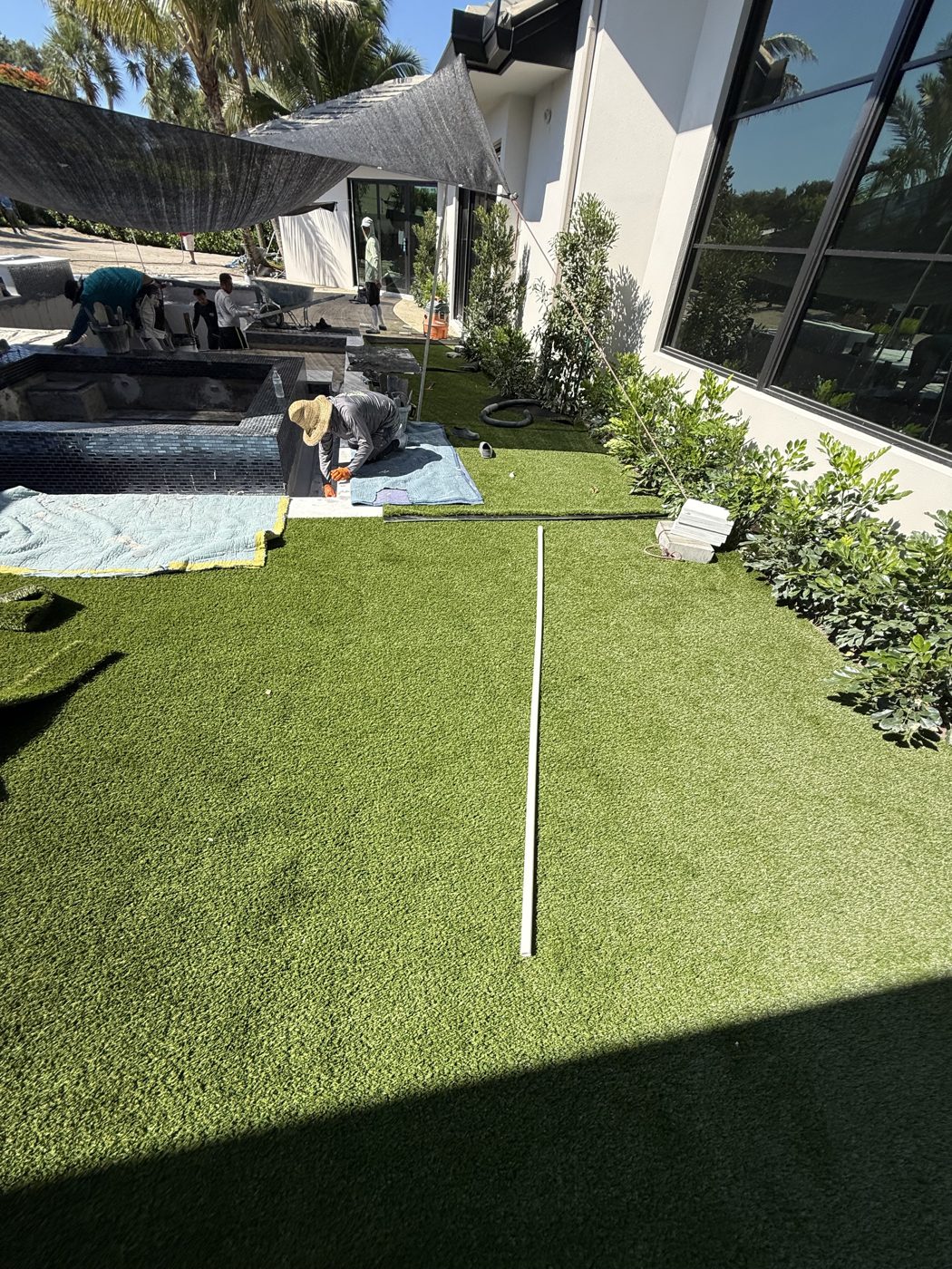 Artificial turf being installed against the marble deck