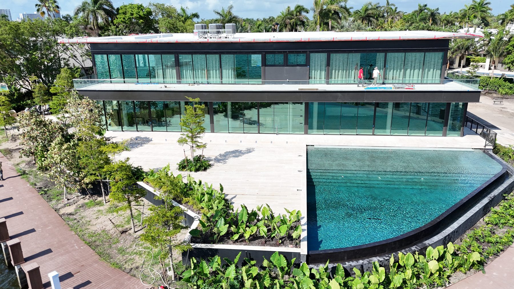 Aerial view of the completed pool along the waterfront with the modern residence behind it