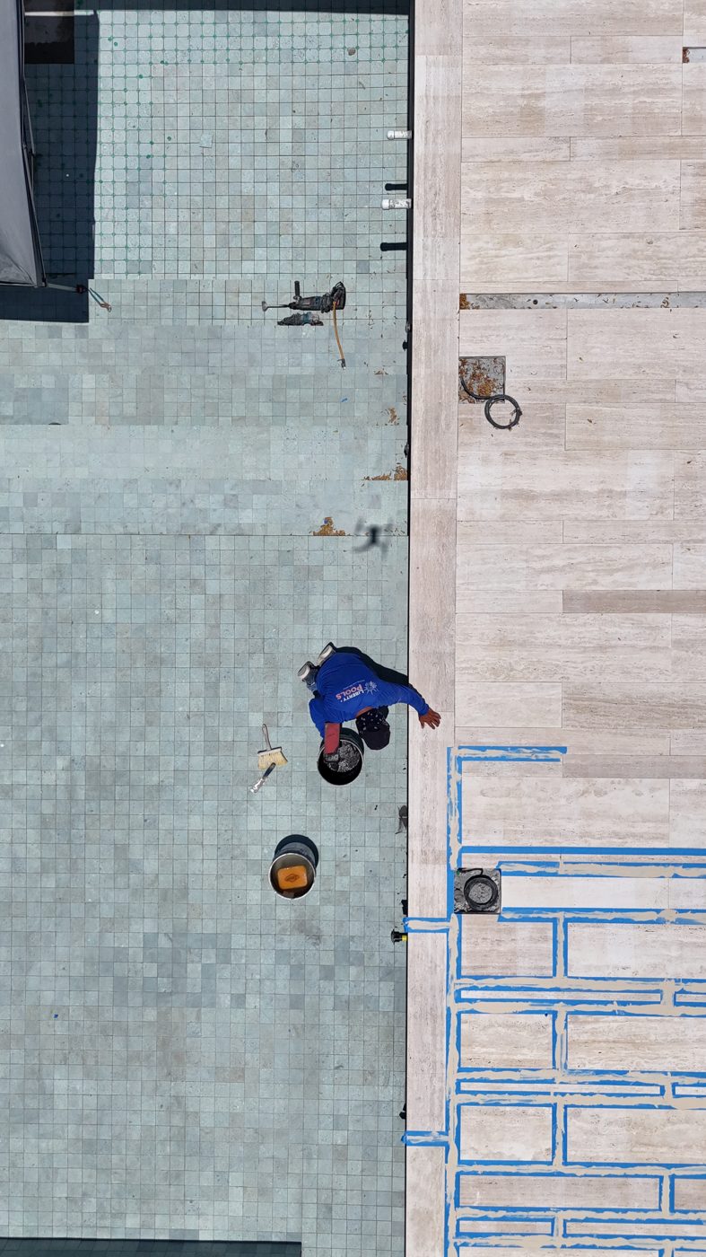 Drone view straight down onto the tiled pool floor and infinity gutter