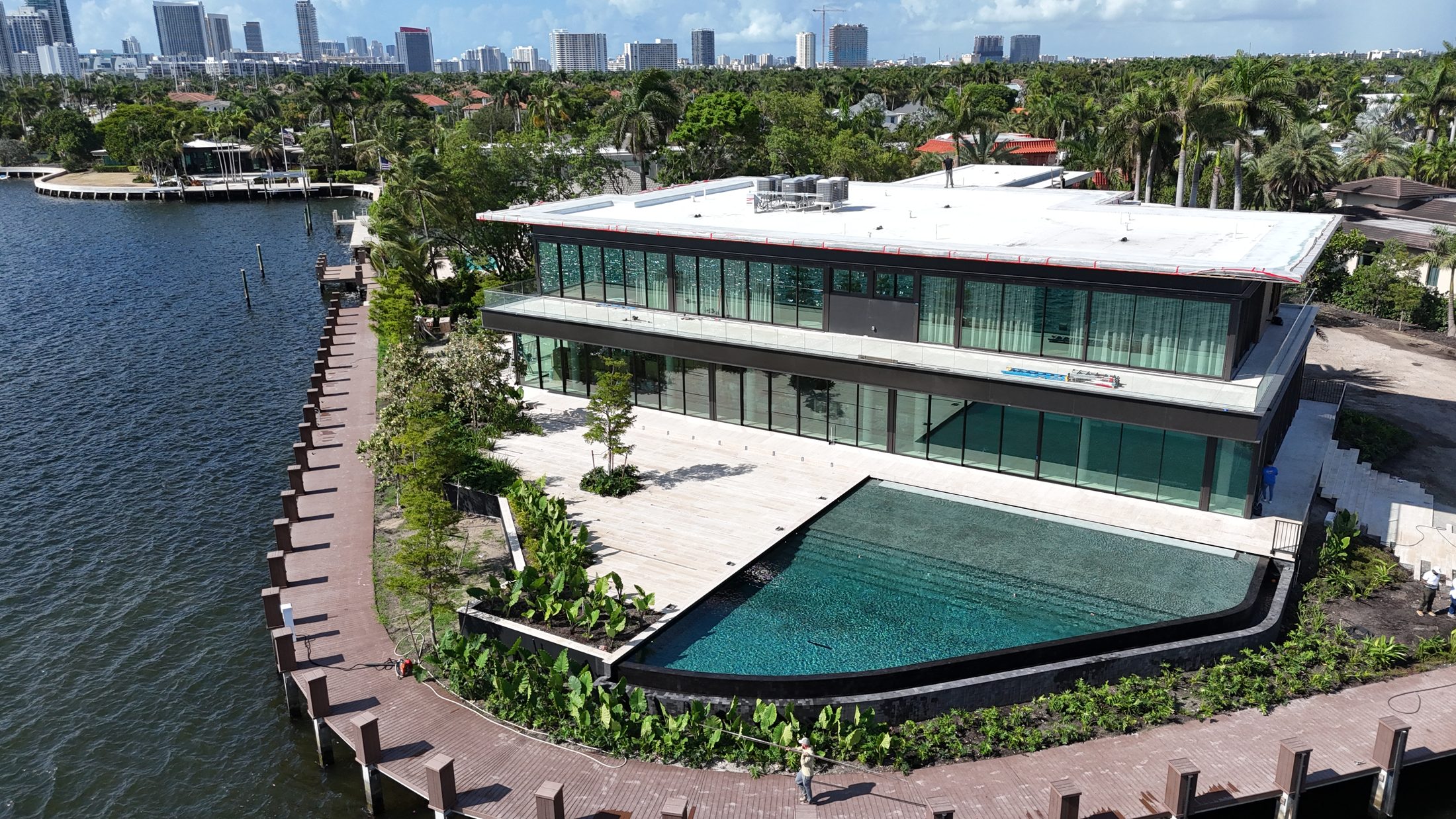 Aerial view of the completed infinity-edge pool wrapping the waterfront residence in Hollywood, Florida