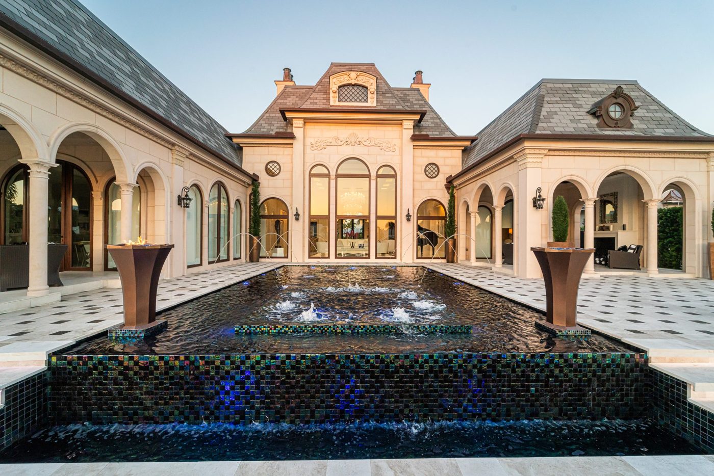 Evening view of the Markovitz pool with fire bowls and deck jets in Jupiter