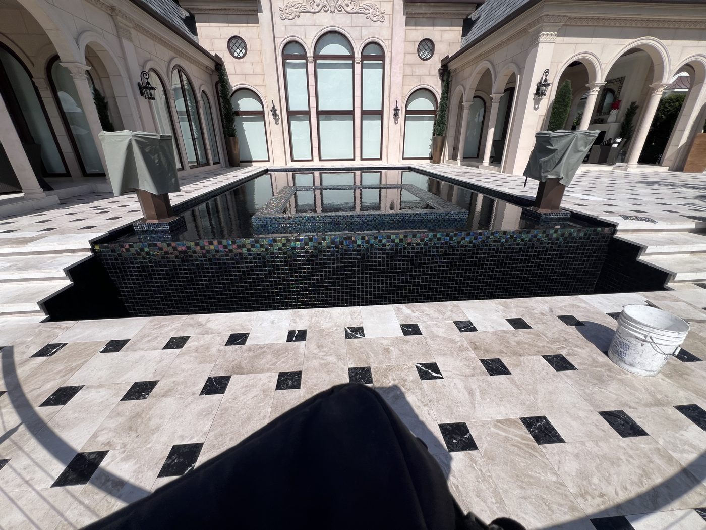 The finished pool and deck seen from the house, with the estate's arches behind