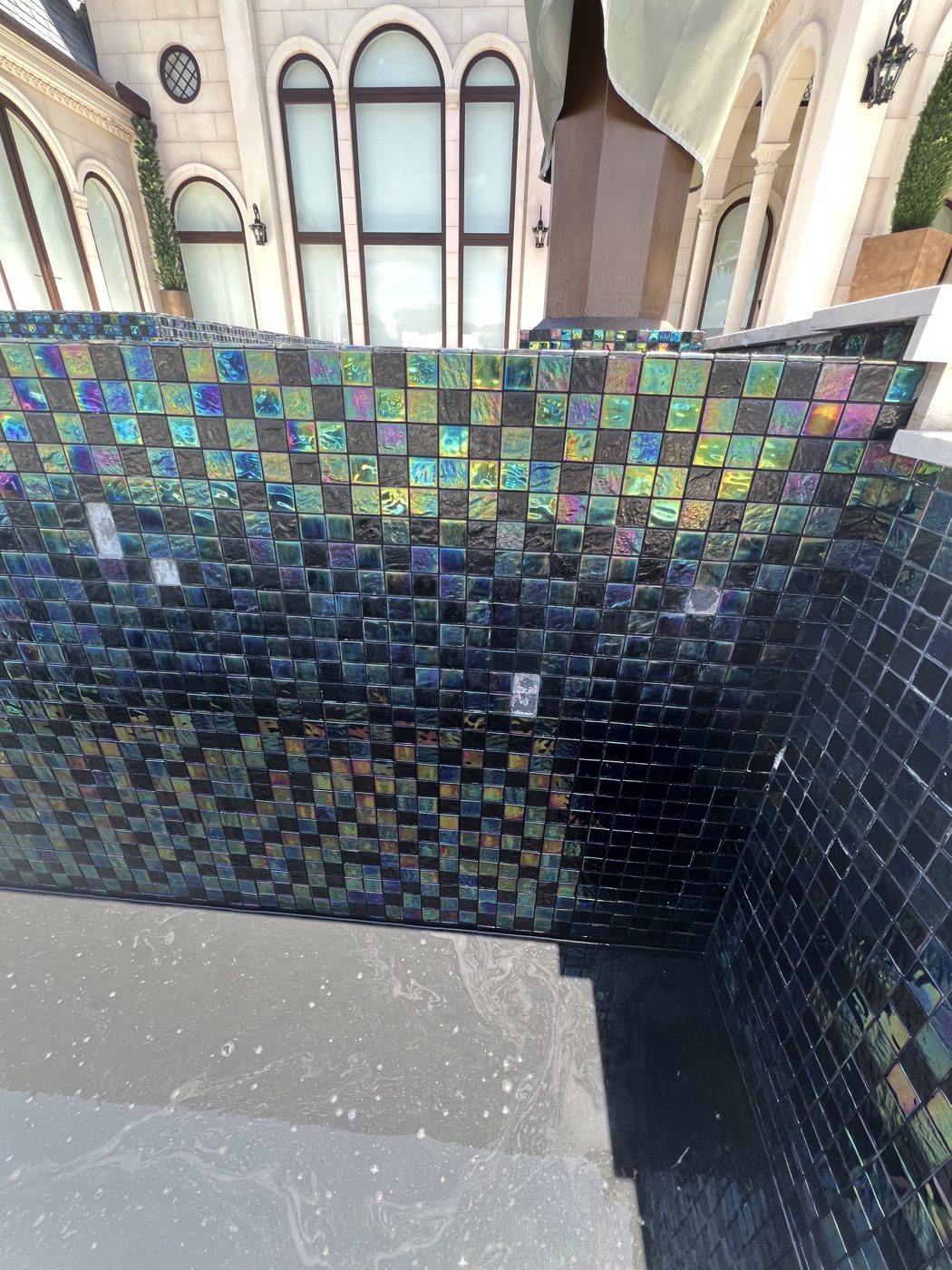 The infinity-edge gutter wall stripped and re-tiled in glass