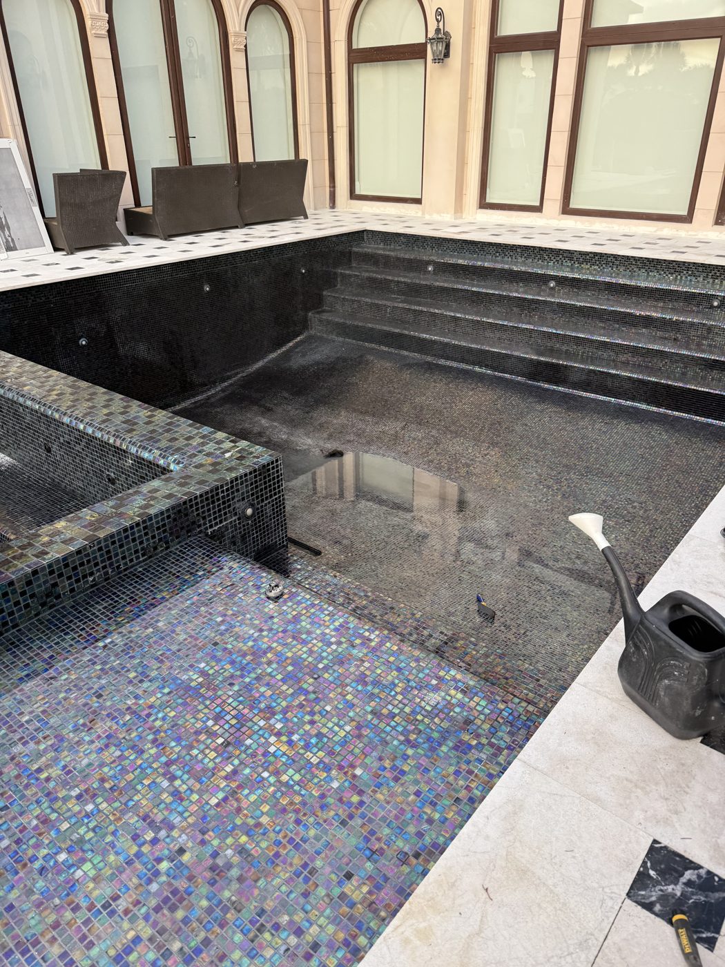The empty pool after re-tiling: new iridescent glass mosaic on the walls and steps, new marble coping