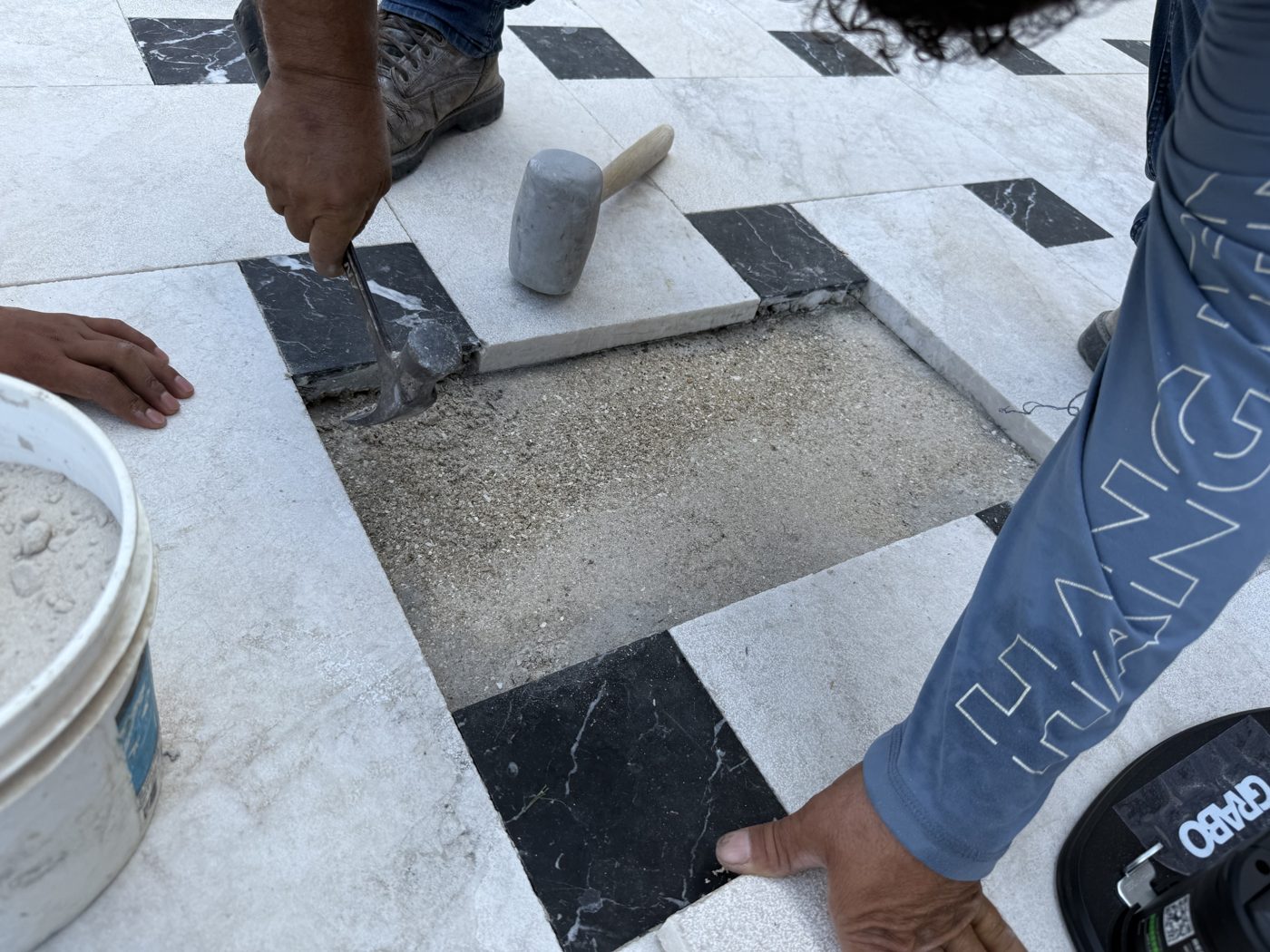 Mason setting a black stone inlay into the marble deck